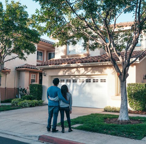 A couple standing in front of their home