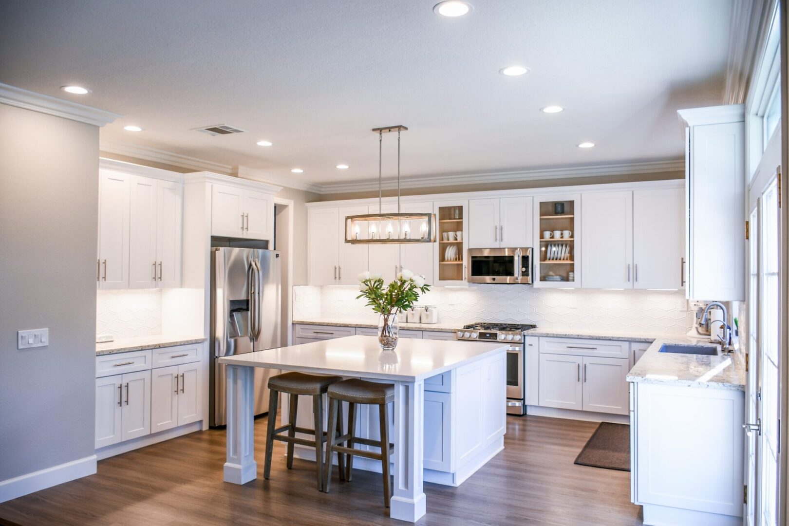 A kitchen with white cabinets and wooden floors