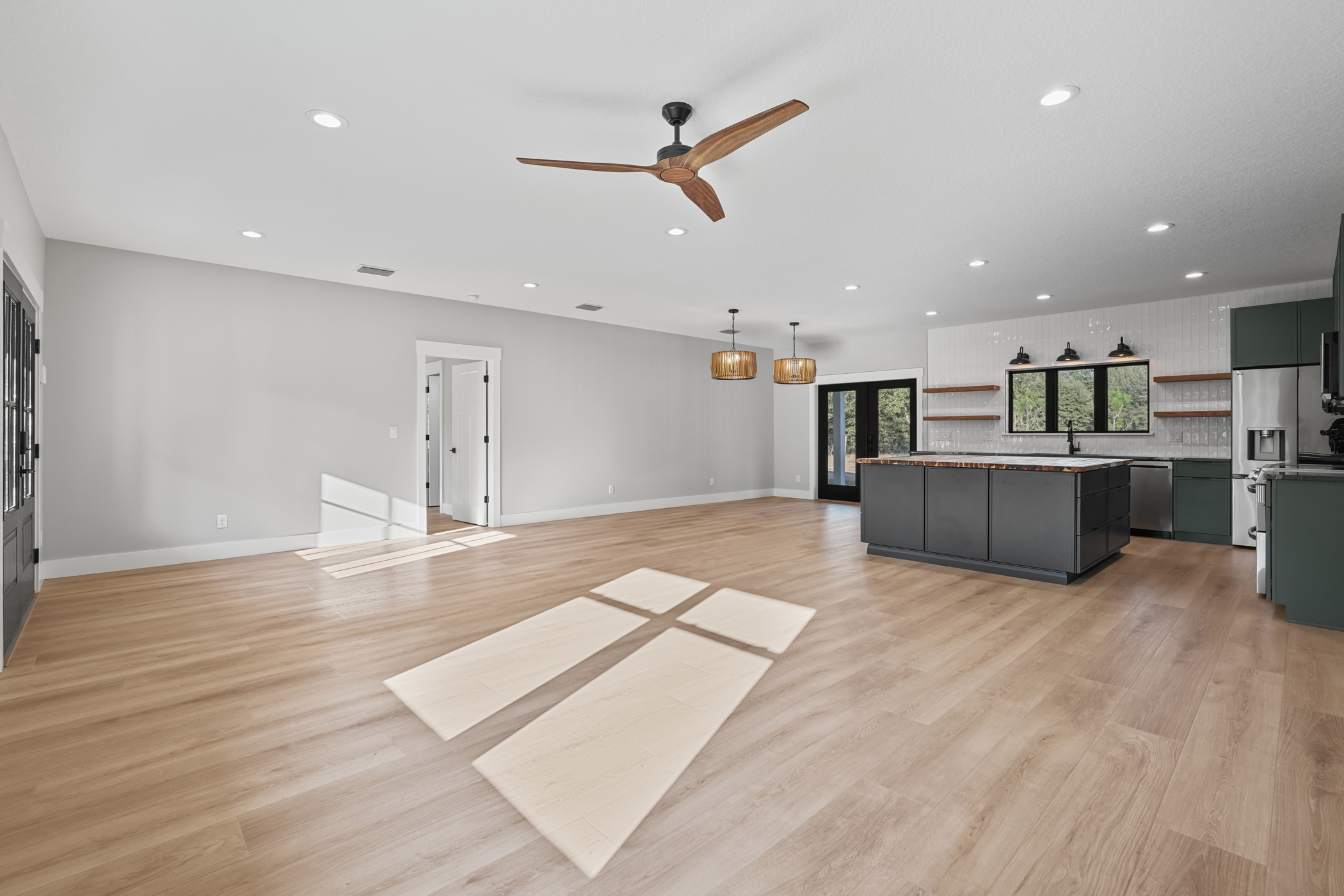 Open-concept living area and kitchen with sage green cabinets, dark island with butcher block top and hardwood floors