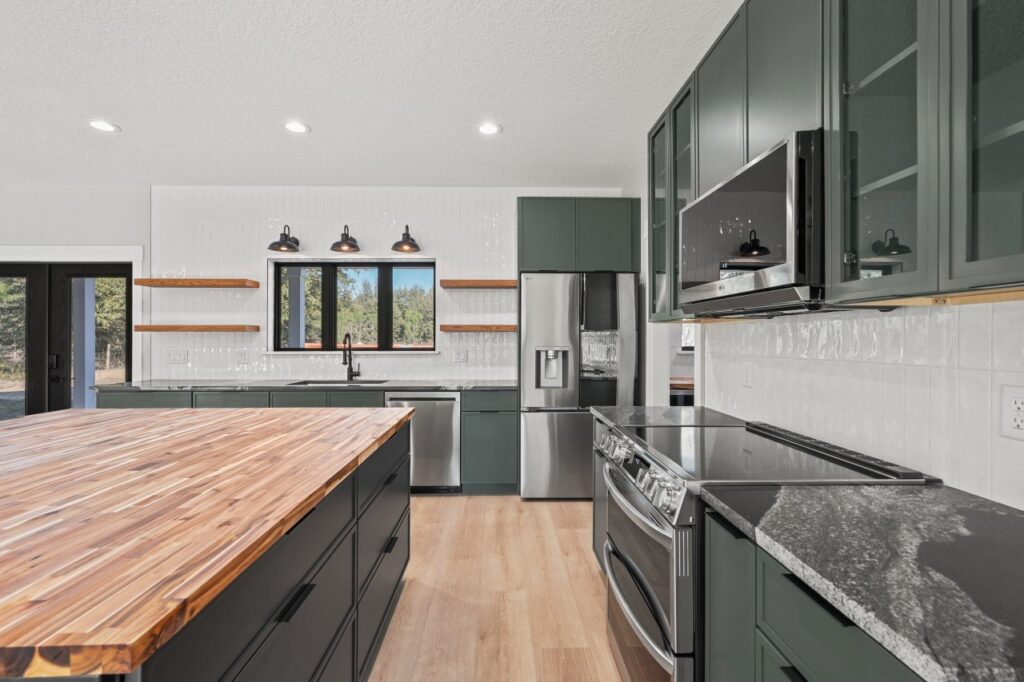 Custom kitchen with sage green cabinets, stainless appliances, subway tile backsplash and large butcher block island