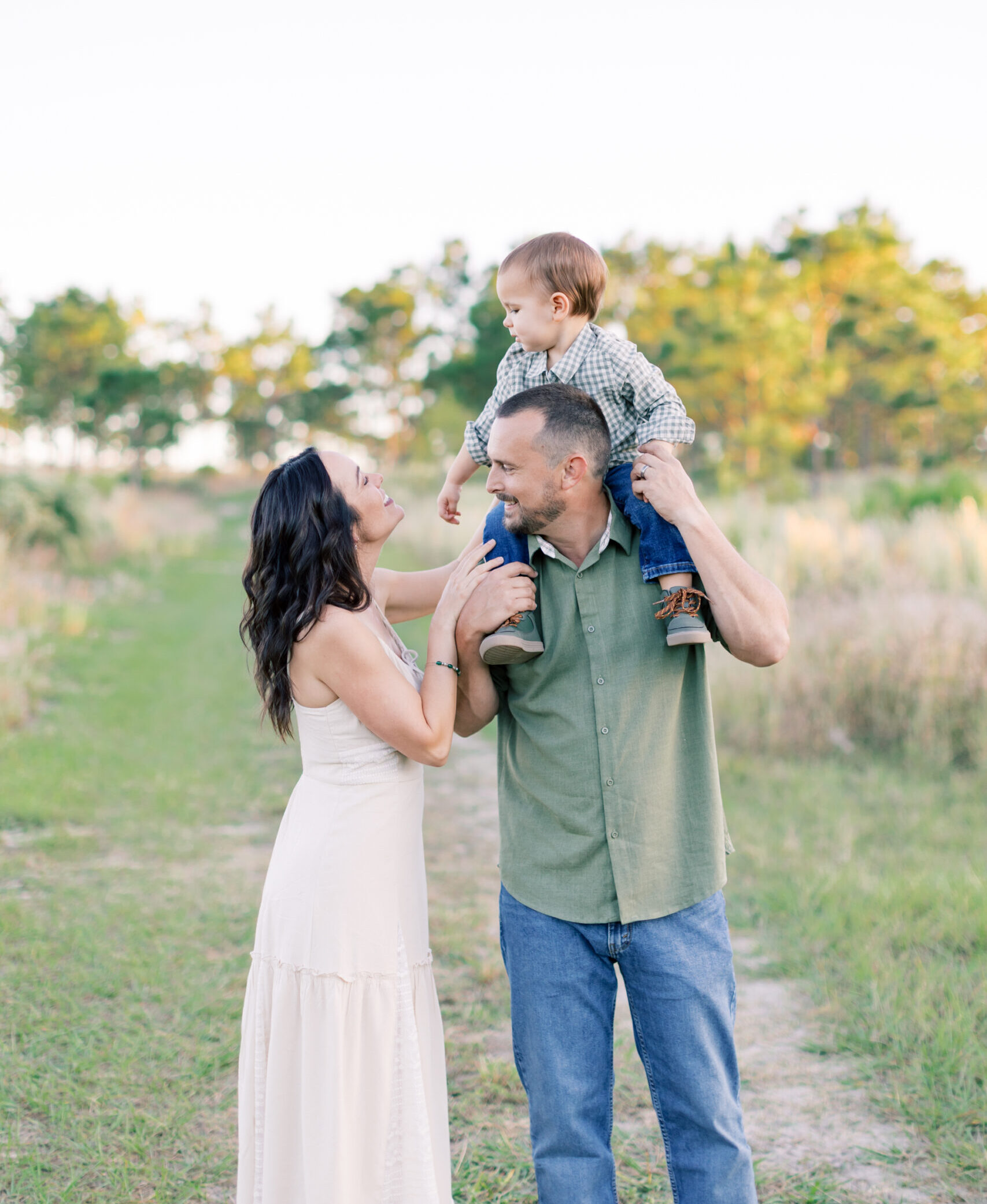 Happy family with father carrying toddler on his shoulders and mother smiling together outdoors