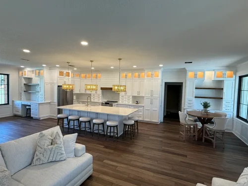 Open-concept kitchen and living room remodel with full-height white cabinetry, large island and dark hardwood floors